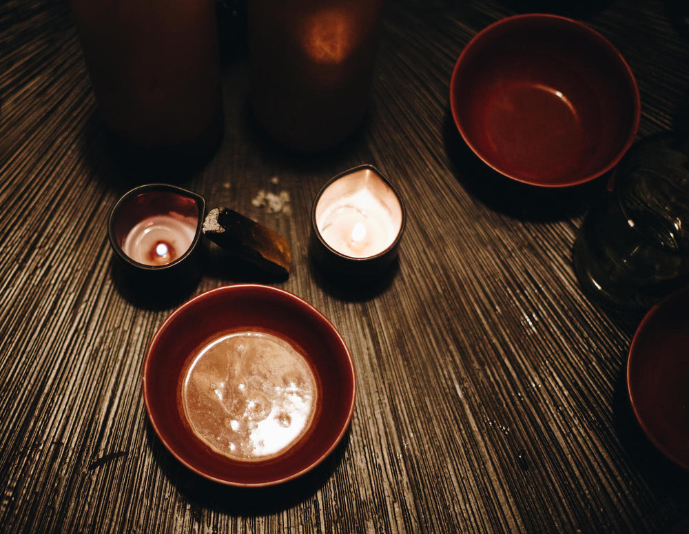 Schale mit Kakao und Kerzen auf einer Bambusmatte