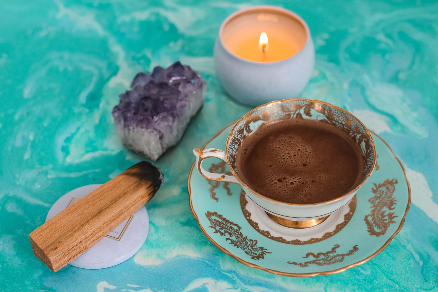 Eine Tasse Kakao in einer dekorativen Tasse mit einem Kristall und einem Palo-Santo-Stäbchen